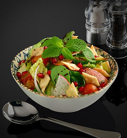 Fresh vegetable cuts including romaine lettuce, cucumber, tomato, red radish, white onion, baqli leaves, mint leaves, rocca leaves, sumac powder and lemon oil dressing garnished with fried toasted bread.