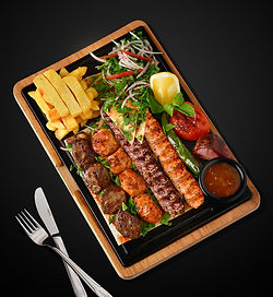 Grilled meat skewer, shish tawouk, grilled adana kebab, chicken kebab, served with biwaz (a mixture of parsley, sliced onions and Sumac), grilled tomatoes, onions, chilli pepper and french fries.