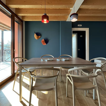 Zona pranzo con tavolo in legno e lampade a sospensione colorate - appartamento arredato a Treviso