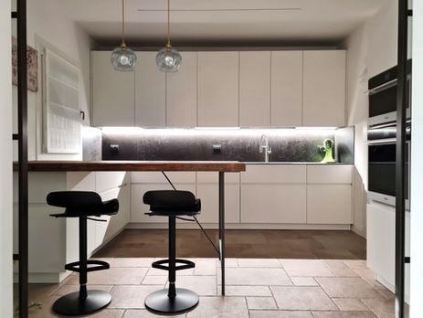 Cucina moderna Valdesign bianca con piano in gres nero effetto materico, LED sottopensile e bancone snack a sbalzo