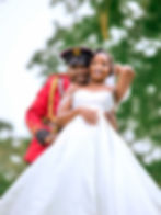 Groom in red military uniform embracing bride in white gown