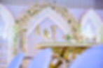 Wedding head table with A&V initials and floral arch.