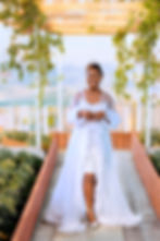Smiling woman in a long white gown on a garden walkway