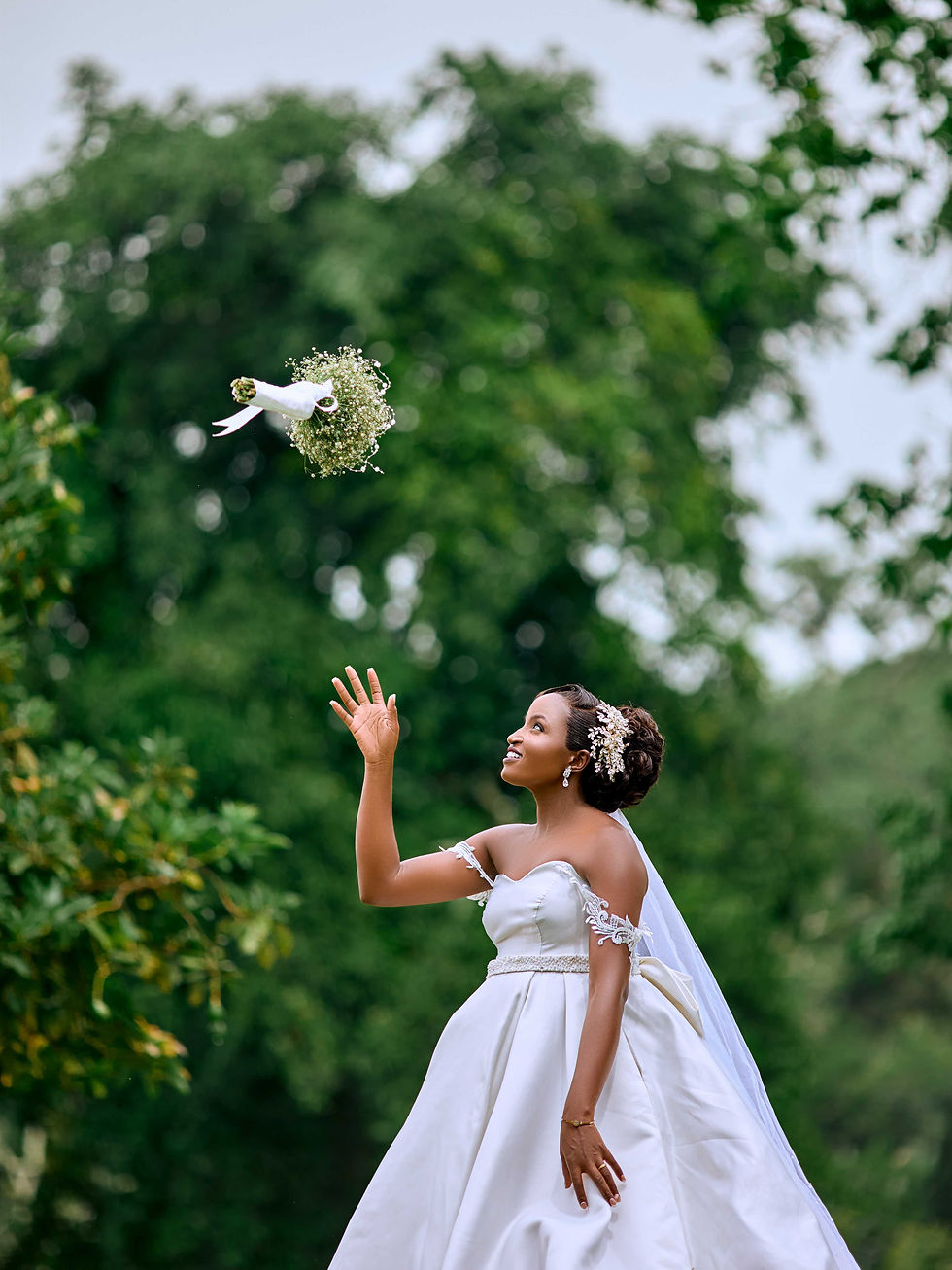 Bride in white gown tossing her bouquet outdoors