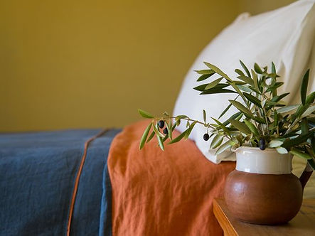 Handcrafted linen duvet and olive bouquet in small country style room..