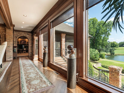 Architectural interior with wood-framed windows overlooking landscaped grounds and a water feature.