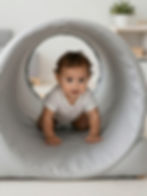 Baby crawling through a play tunnel at nursery and daycare