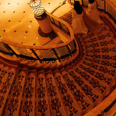An ornate chandelier and curved staircase create an elegant arrival setting inside the venue.