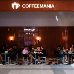 Wide view of guests dining in the warmly lit Coffeemania restaurant at Dubai Hills Mall.