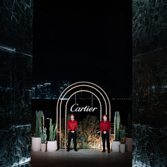 The team stands beneath the glowing Cartier entrance arch, framed by reflective black walls after nightfall.