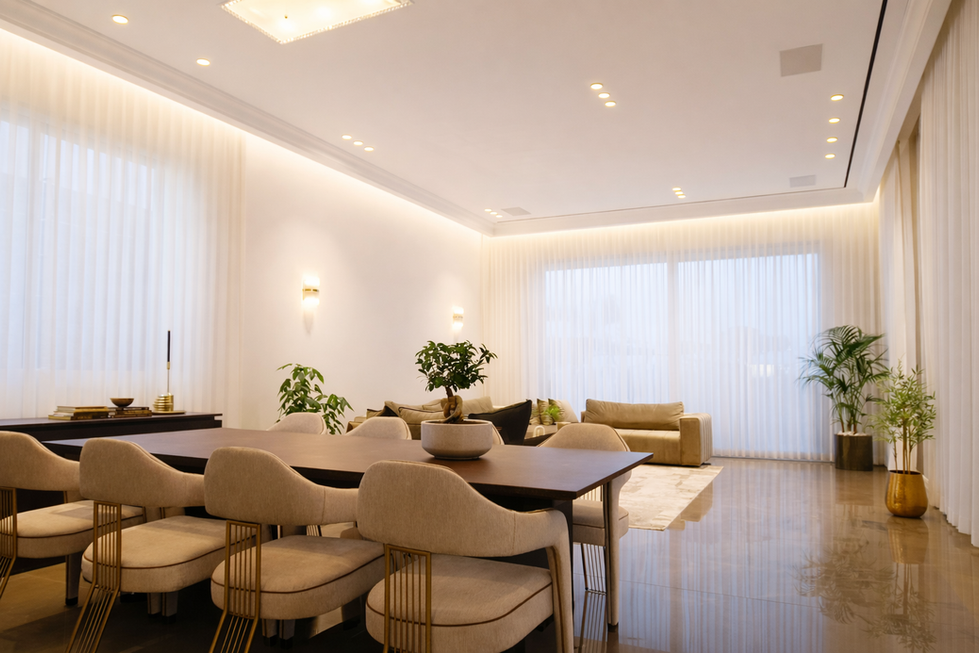 Luxury villa dining and living room with large dining table, upholstered chairs, warm lighting, and floor-to-ceiling curtains in Abu Dhabi UAE.