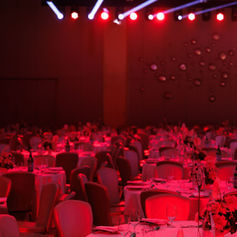 Ballroom tables prepared beneath red stage lighting for the HOLM One launch event.