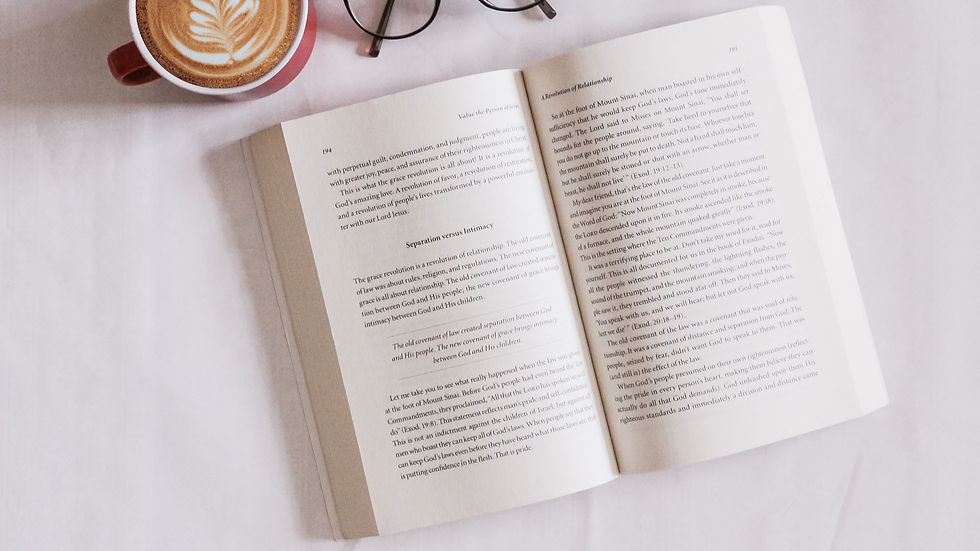 An open book next to a cup of coffee and reading glasses