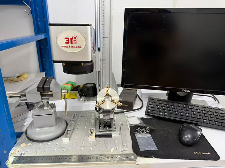 Lab workstation with a 31du camera rig, vise, monitor, keyboard and mouse on a metal test bench; DELL and Microsoft visible.
