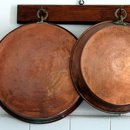 Three Copper pans hanging up together.