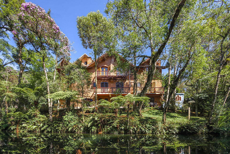 Casa sede da Estalagem Spiller com fachada em tons de terra, cercada por uma floresta exuberante.