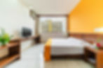 Suíte do Alice Vitória Hotel Arte com cama box, escrivaninha, televisão e janela com vista para a cidade de Vitória