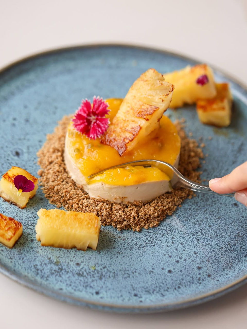 Vista aproximada e focada do momento em que uma colher de sobremesa retira um pedaço de um doce gourmet, servido no Restaurante Alquimia no em Campos do Jordão.