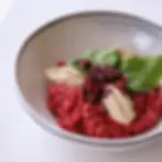 Vista aproximada e focada de um risoto de beterraba com coloração vermelho-intensa, servido em um bowl de cerâmica clara no Restaurante Alquimia no em Campos do Jordão.
