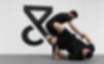 Two men in the middle of a jiu-jitsu or grappling session on a mat. The man in the foreground is lying on his back, wearing a black t-shirt and black shorts with a gray or black stripe on one leg. Trein Fort Bend in Sugar Land, TX, USA.