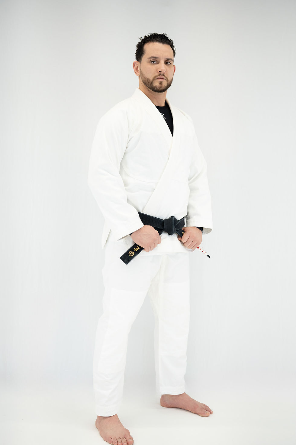 Bearded man, the lead teacher at Yoga & Trein Houston and a Jiu-Jitsu champion, wears his white gi and black belt. He represe