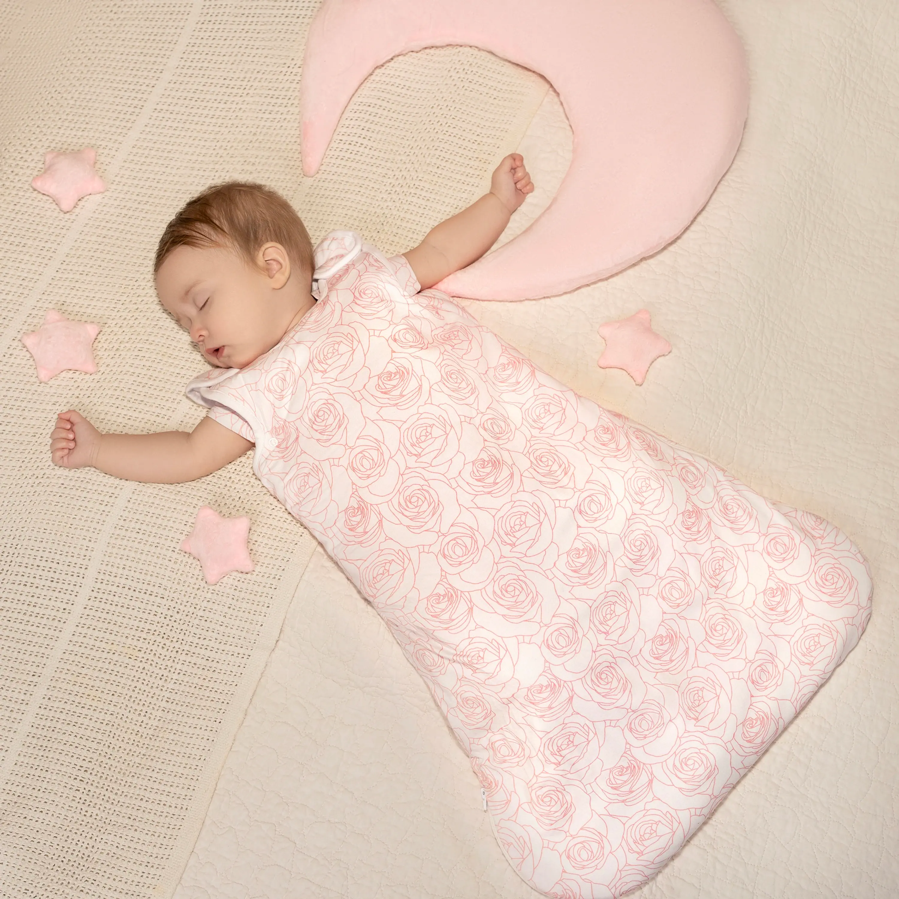 Baby sleeping peacefully in a rose patterned baby sleeping bag.