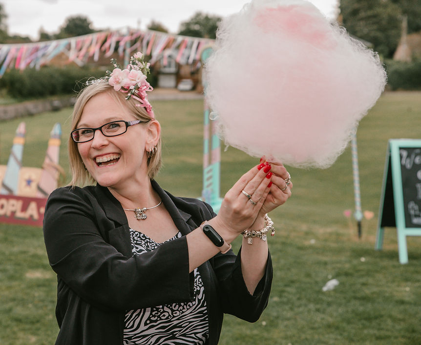 Guest smiling while holding pink candyfloss at an outdoor wedding with lawn games and carnival-style props, provided by a wedding games hire company