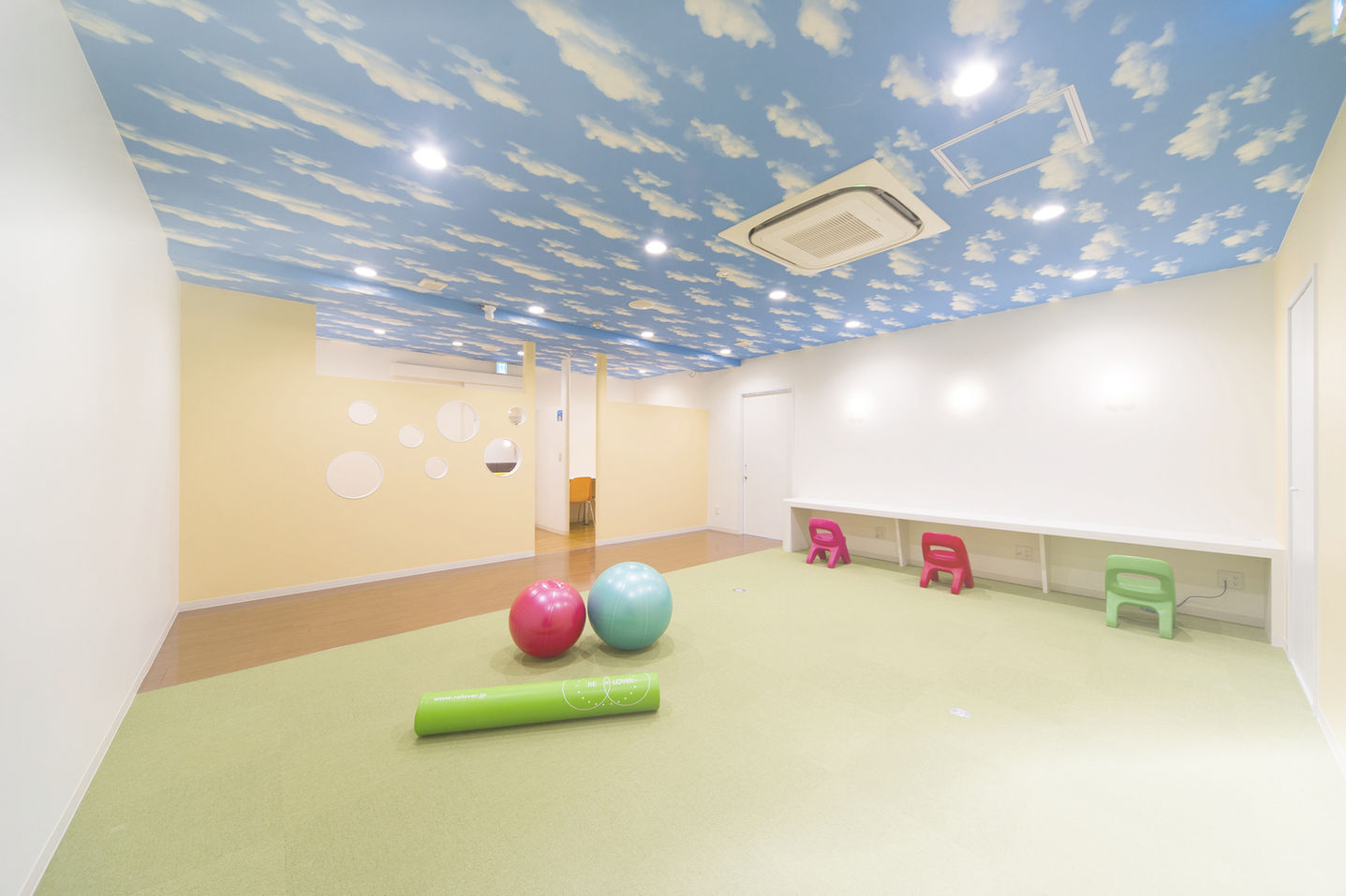 青い雲模様の天井と、ボールなどがある子供向けプレイルームです。