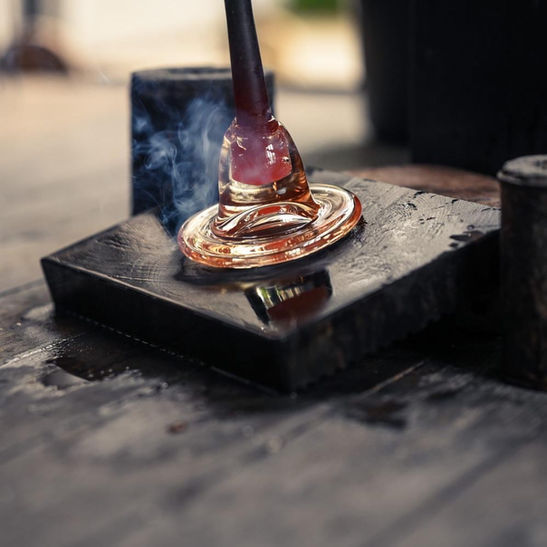 Glassblowing on wet wood, a precise and traditional technique used in glass production.