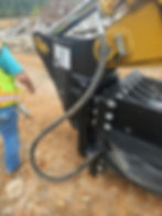 Worker performing heavy equipment repair on an excavator attachment