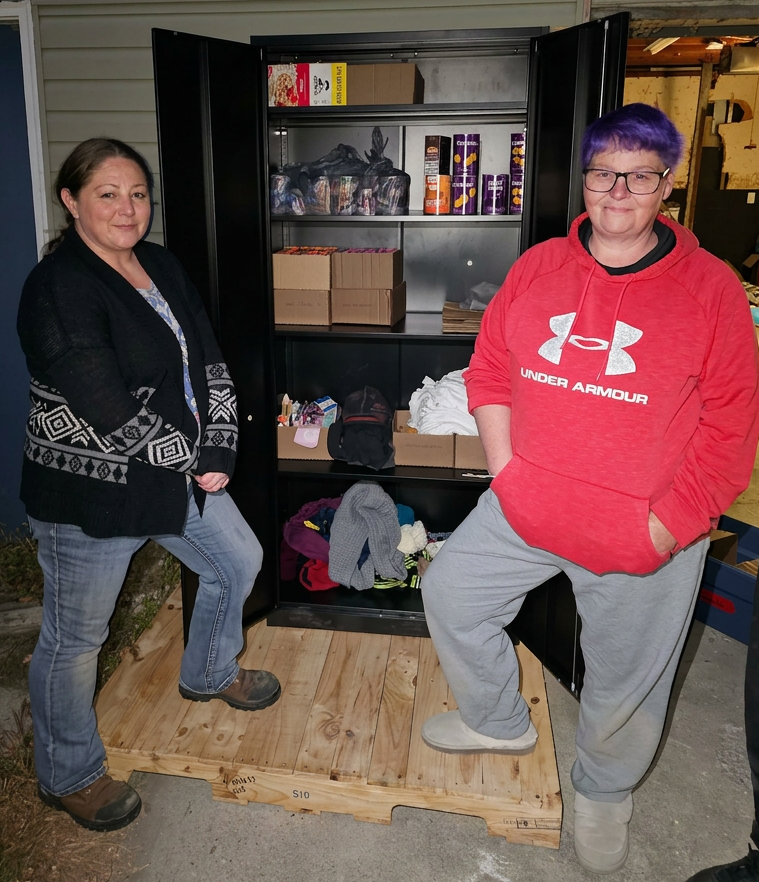 Two Progressive Democrats standing in front of a cabinet they filled with food and clothing for those in need in Clinton County, Indiana