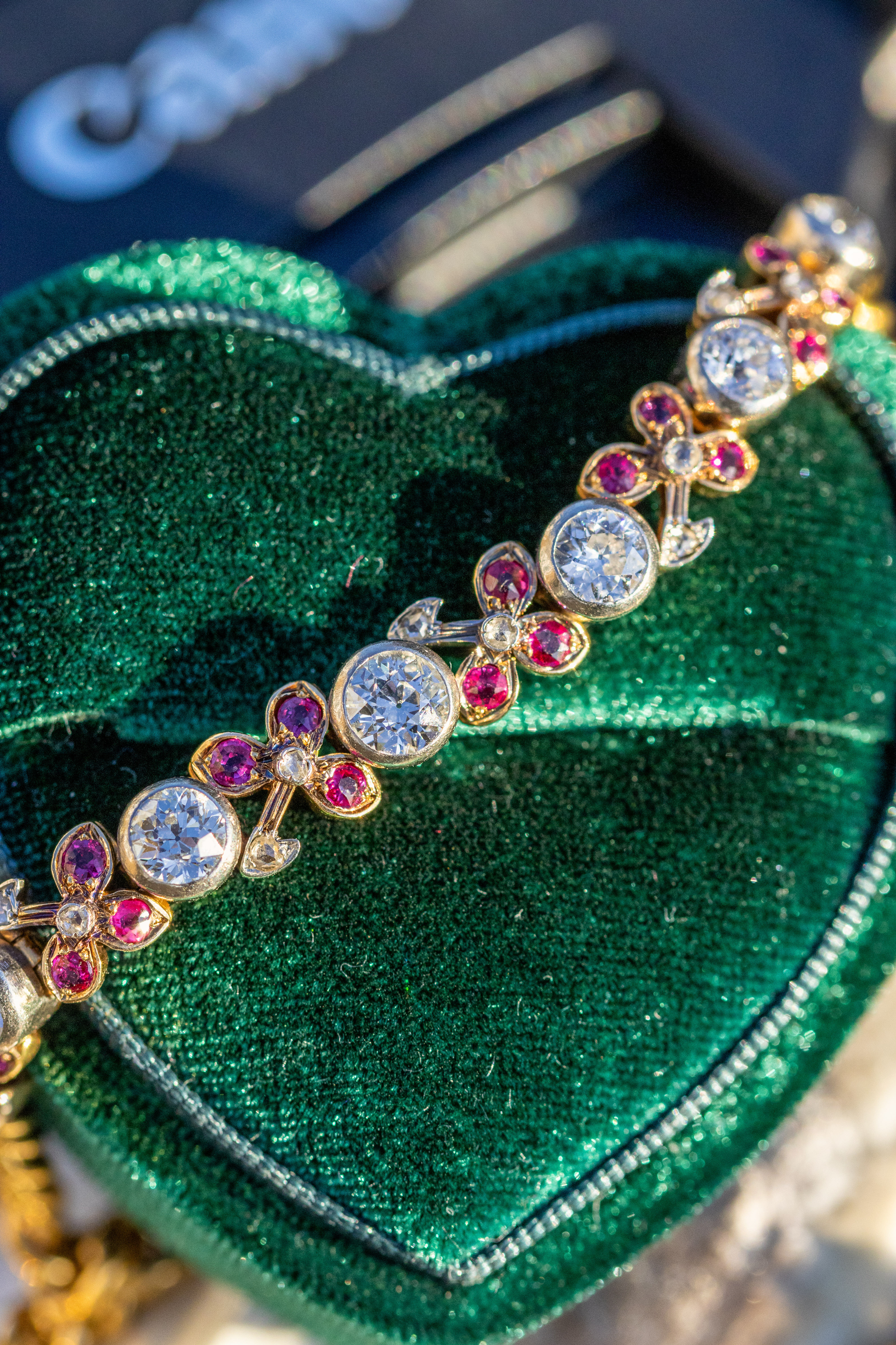 19th-century antique diamond and ruby bracelet held in sunlight showing sparkle and floral detailing