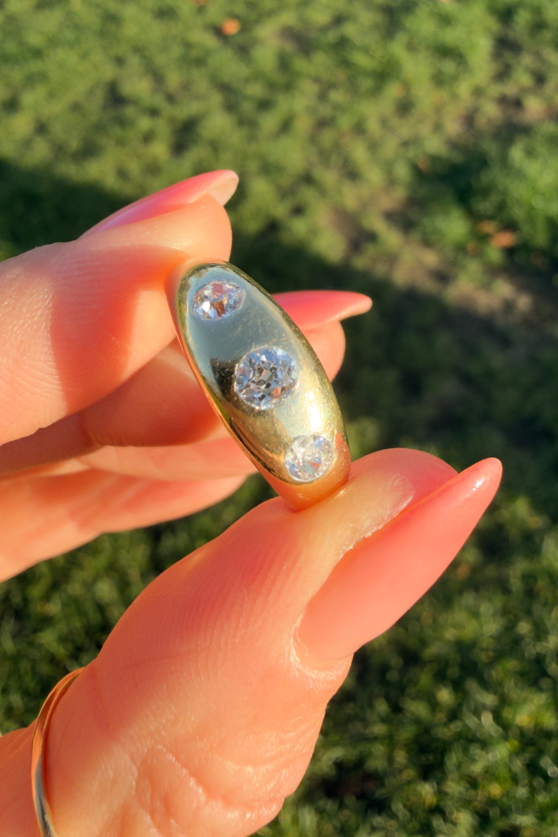 The antique three-stone gypsy ring in 18ct gold shown held with the diamond facing forward.