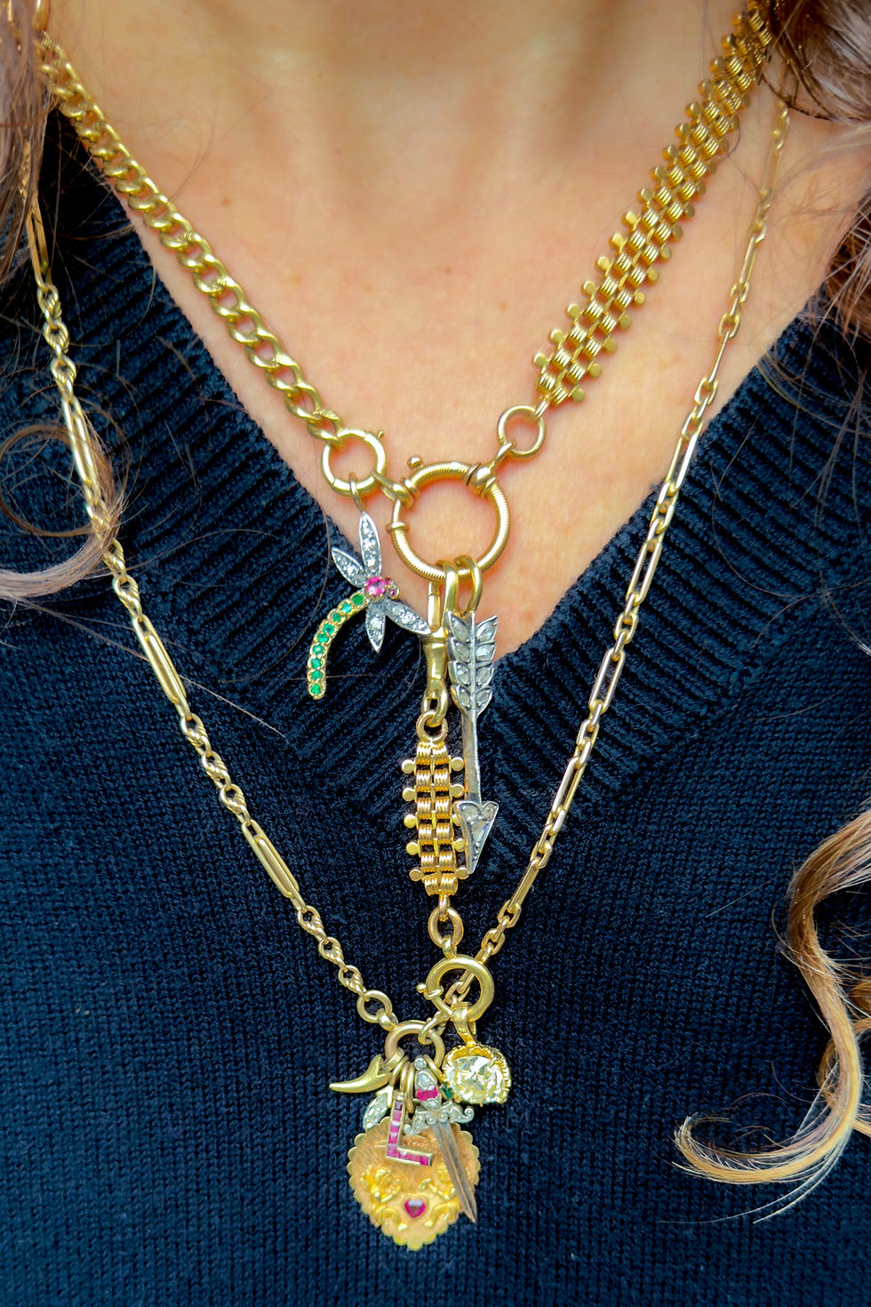 Thumbnail: Antique gold watch chain necklace worn with an additional extender in a lariat style with charms and pendants.