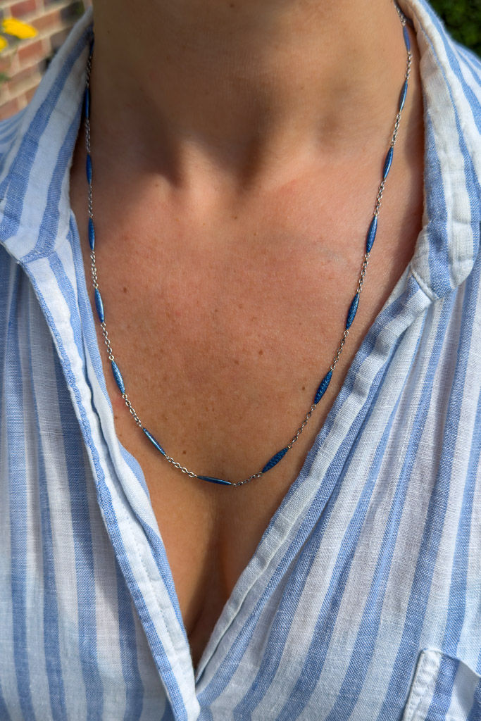 Close-up of antique platinum station chain featuring elongated cobalt blue enamel links with geometric chevron decoration.