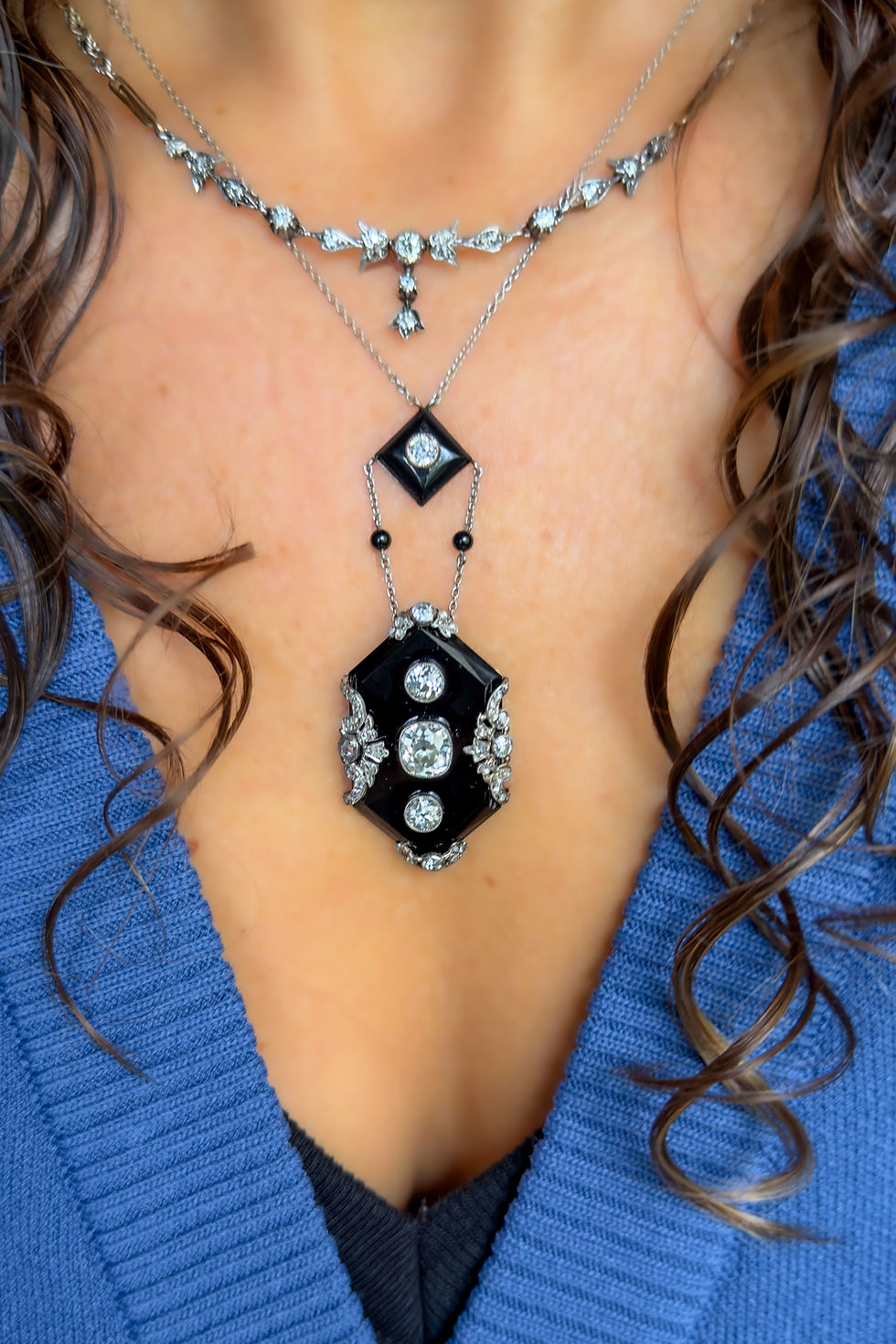 Model wearing platinum onyx and antique diamond pendant necklace.