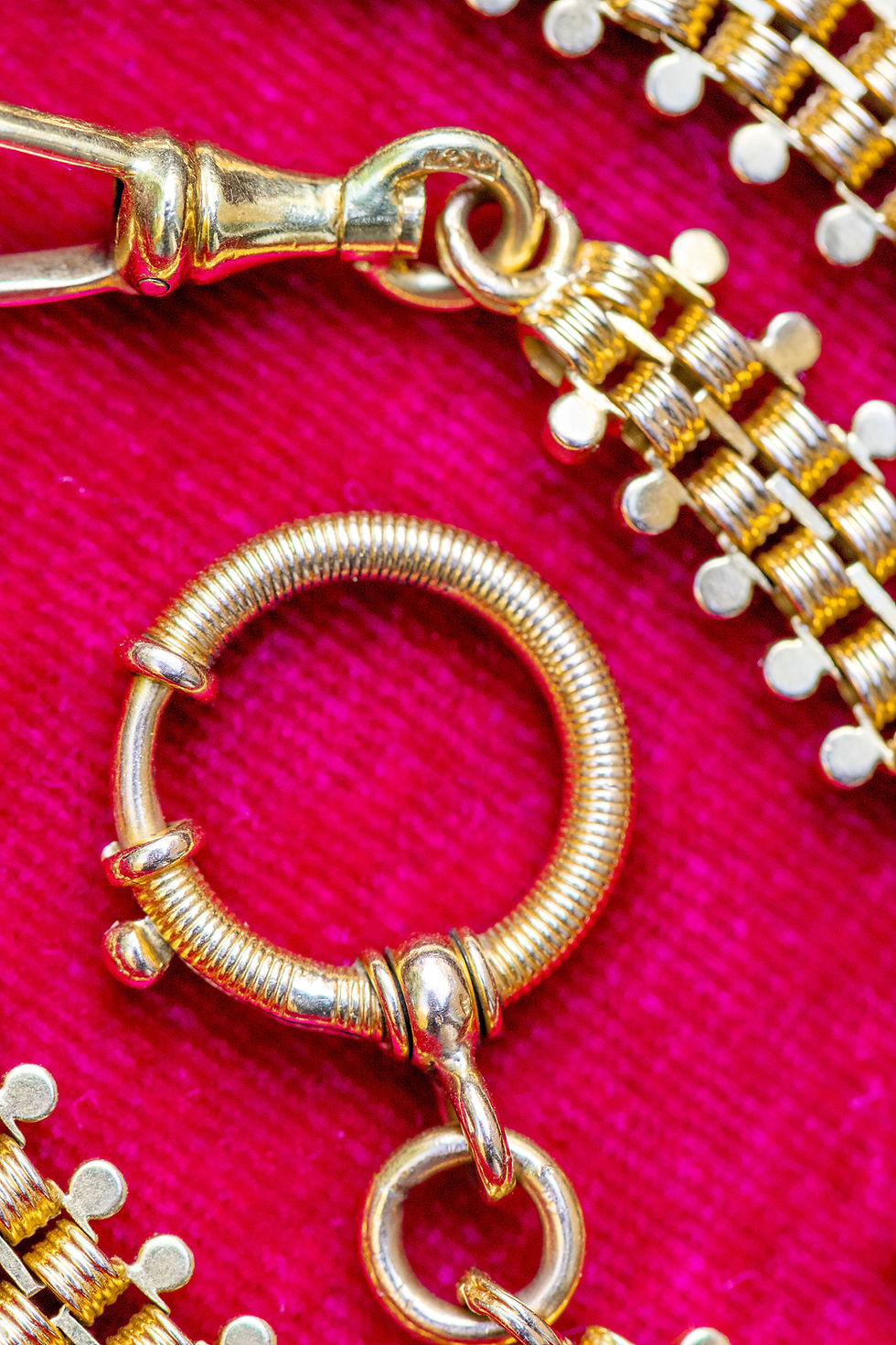 Thumbnail: Macro close-up of 18ct gold repoussé watch chain showing big bolt ring clasp on red velvet background.