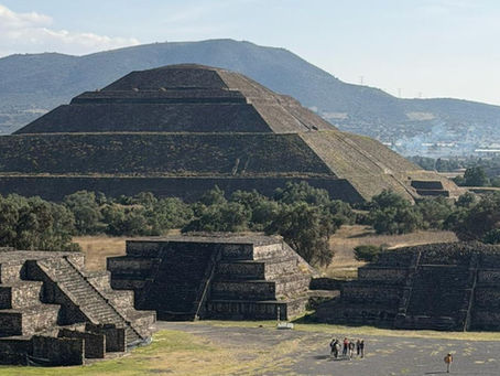 Vista da Pirâmide do Sol em Teotihuacán, no México, com plataformas menores ao redor e visitantes caminhando no primeiro plano.