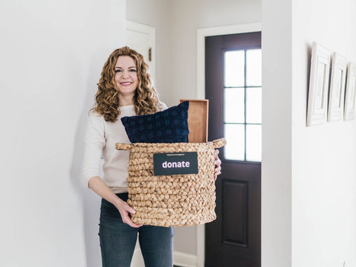 Woman standing with a basket and assorted items to donate to a local charity
