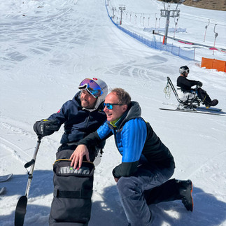 Carlo e Mauro sulla neve. Mauro è sugli sci adattati e Carlo vicino a lui