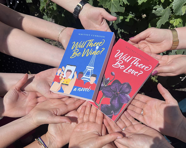 Many hands holding a copy of Will There Be Wine? and one of Will There Be Love?