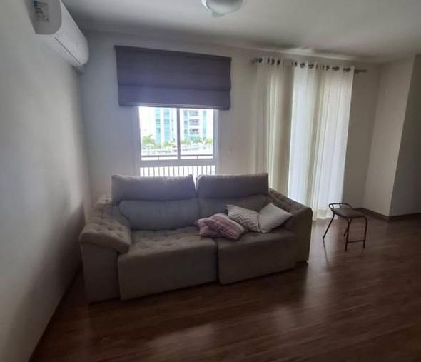 Sala com piso de madeira, cortinas e sofá