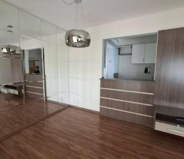 Sala bem iluminada com piso de madeira, cortinas e sofá e espelhos