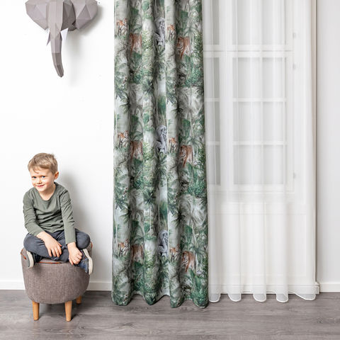 Boy poses with elephant decoration, patterned DRAPERY, and white sheer curtains.