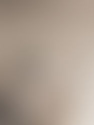 Antique chair with fur pillow and blanket next to a vintage table with patterned vases. Background: beige chevron wallpaper. Cozy mood.