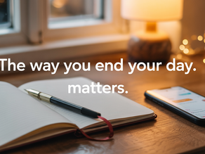 Open notebook and smartphone on a wooden desk by a window. Warm lamp light and fairy lights create a cosy ambience. Text reads, "The way you end your day matters." Good night quotes