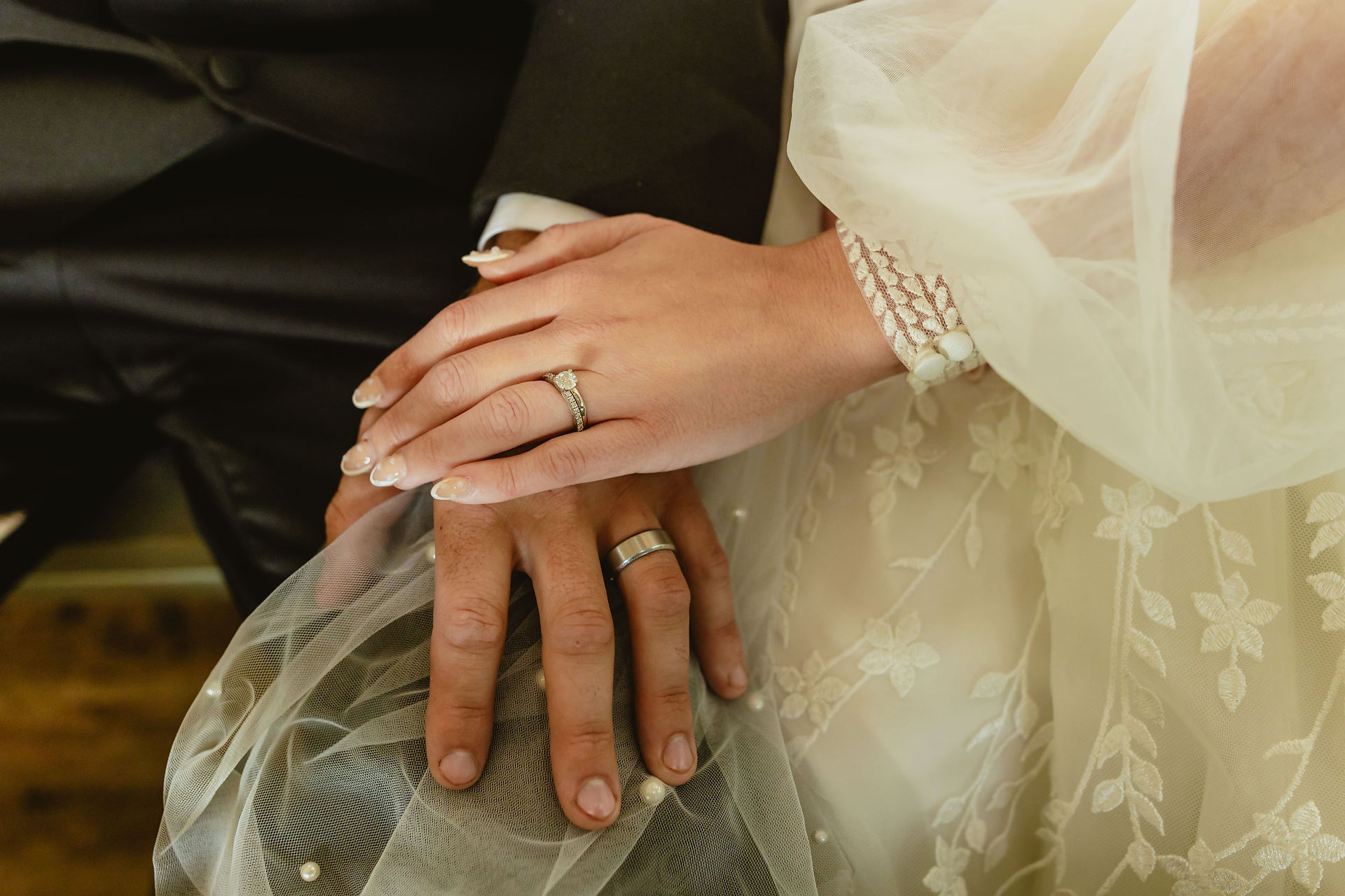Bride and Grooms hand with rings on after ceremony. Their hands are on the groom knee. 