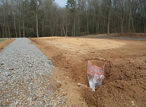 cleared lot with level dirt pad ready for house foundation, gravel driveway cut in with cu