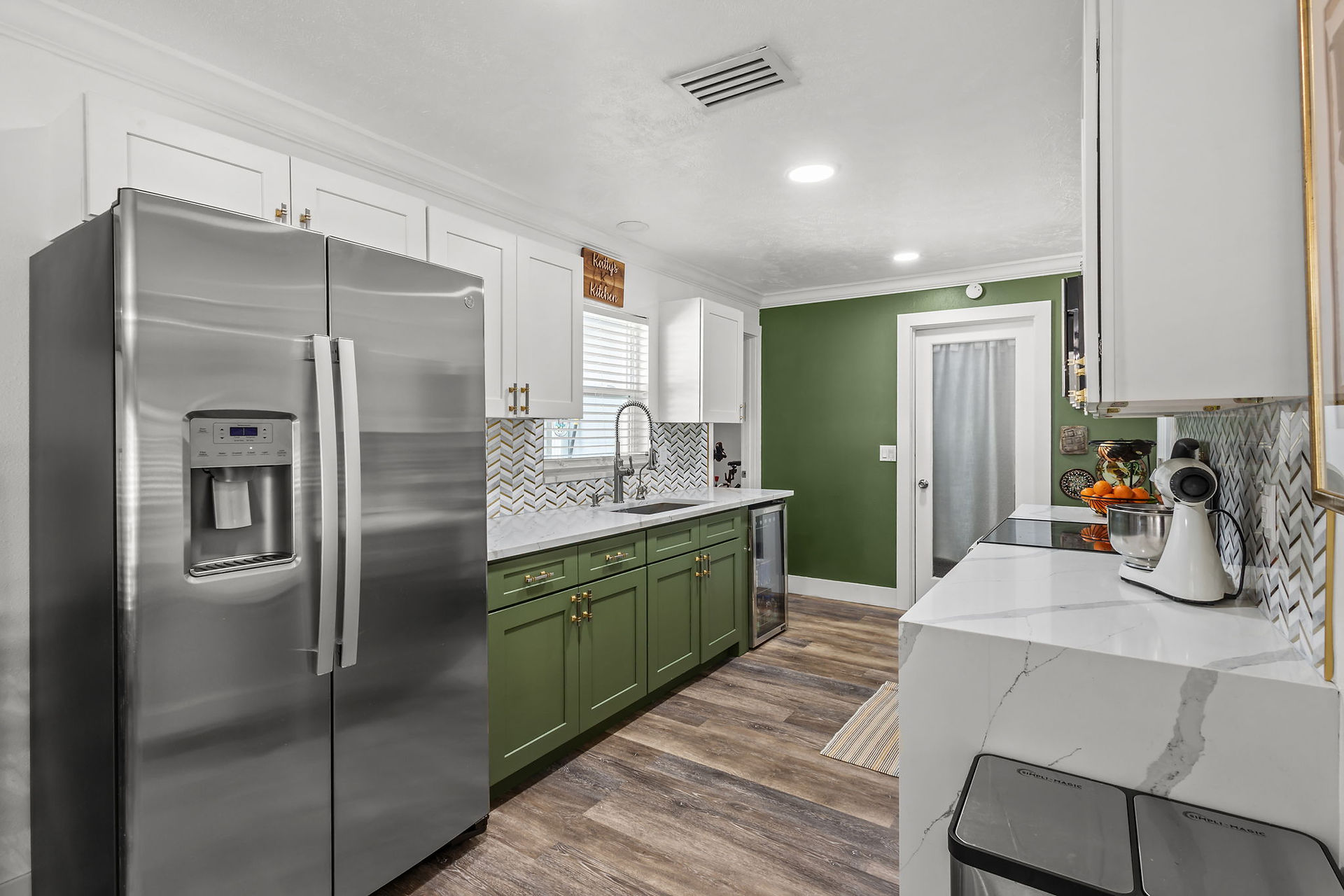 Different view of the kitchen with stainless steel fridge, green accent wall