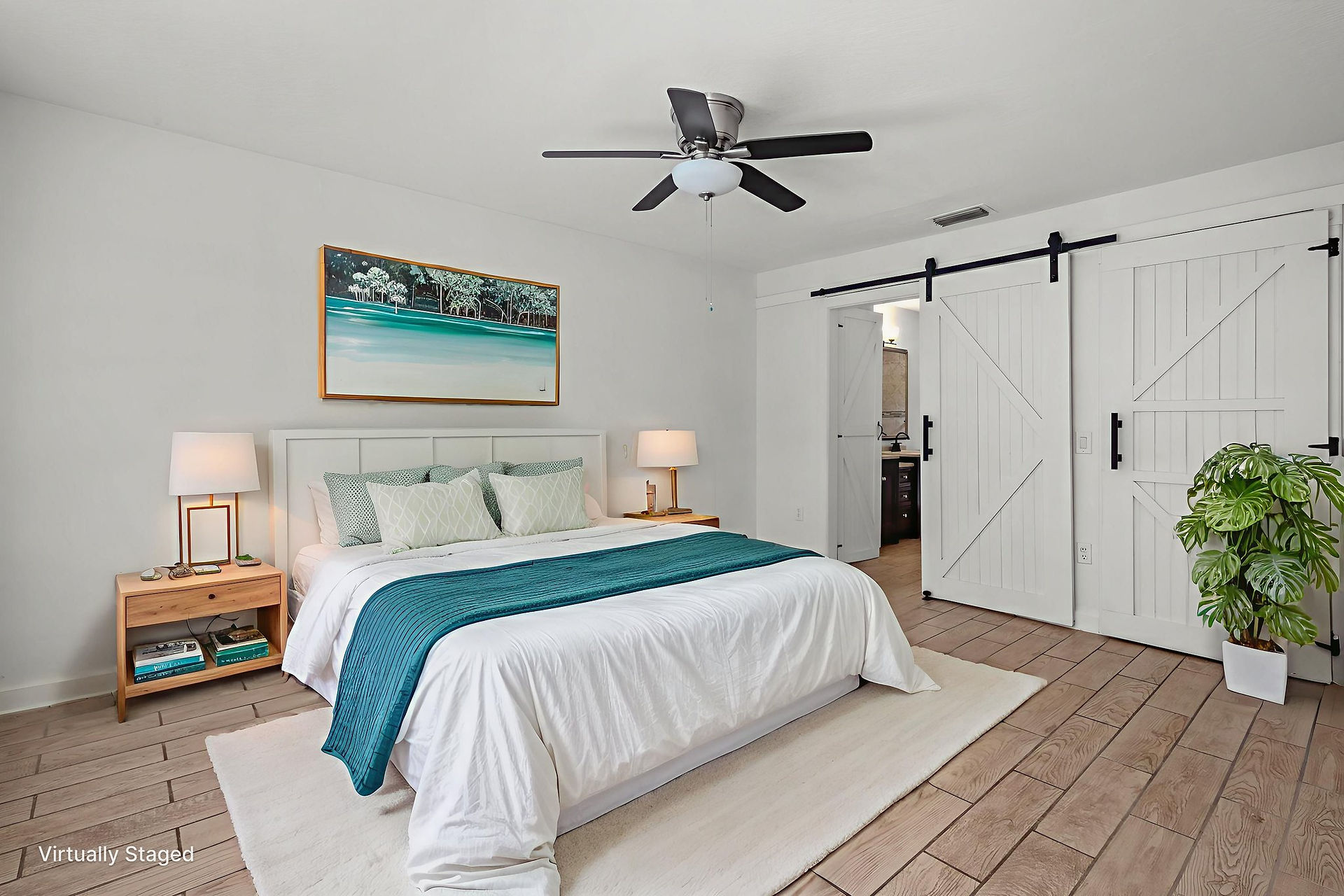 Virtual staged primary bedroom with ceramic tile flooring, white walls, ceiling fan, bed with two end tables, white barn door leading into the master bathroom